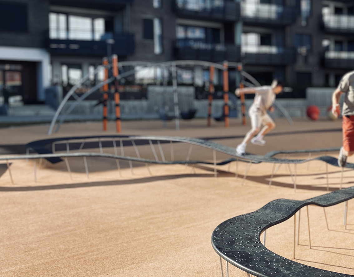 bilde av gutter på lekeplass i Kristiansand, en benk som kan løpes på, benken har bølger og buer og fine former rundt i landskapet på lekeplassen, gutter som løper og har det gøy på lekeplass